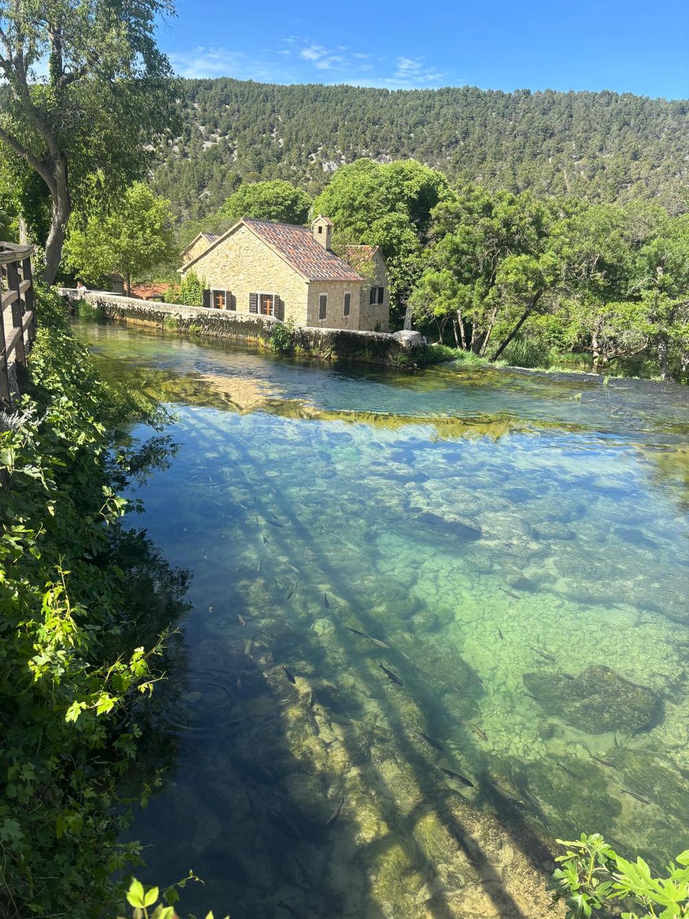 A stone house on the clear, green river at Krka