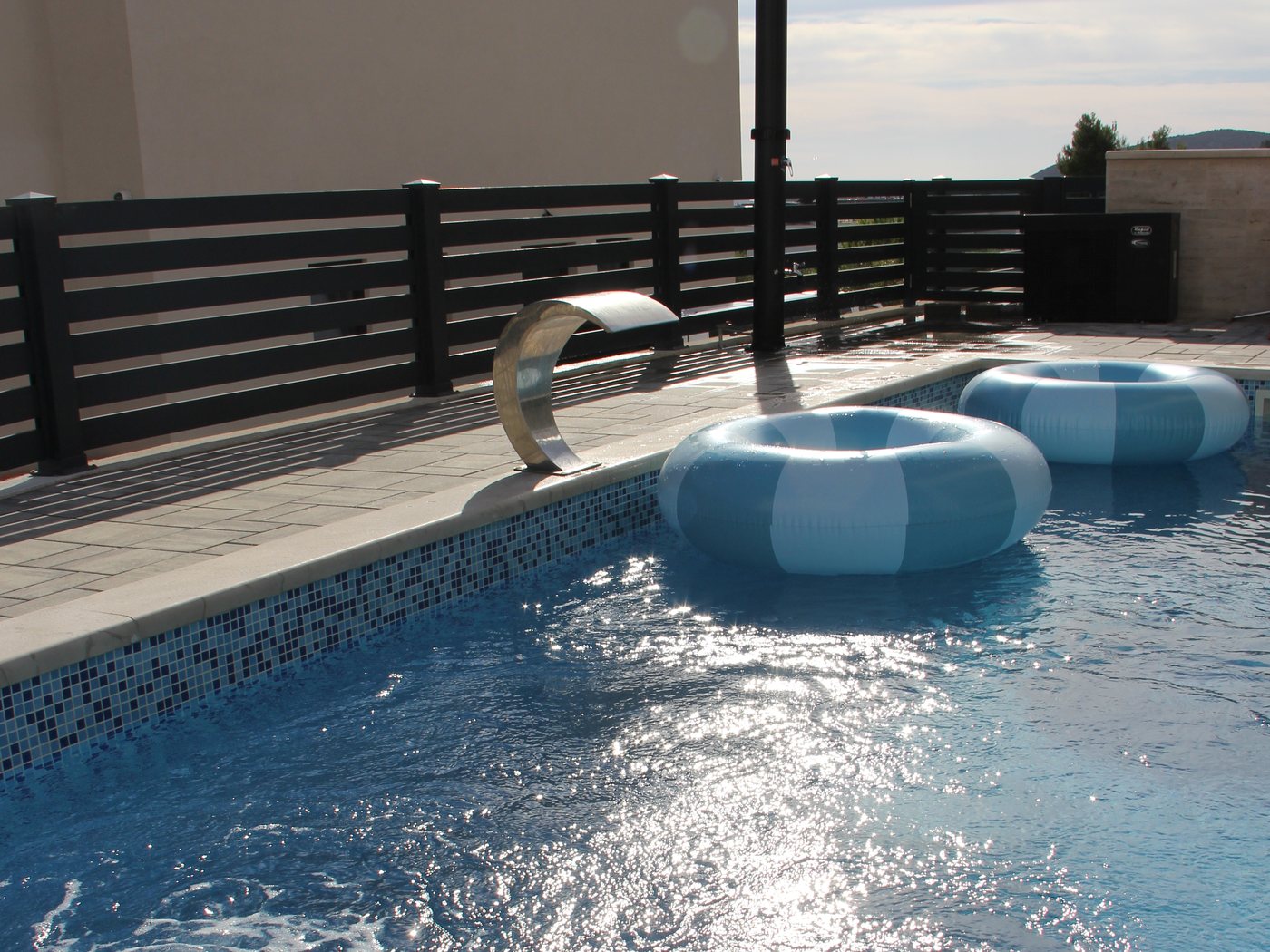 The pool at dusk, with the covered outdoor dining area lit up behind it