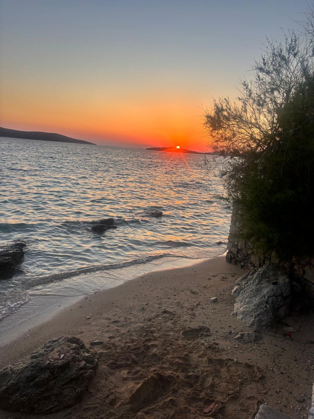 Sunset over the sea from a pebble shore
